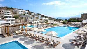 A resort with a large swimming pool, sun loungers, and a view of the surrounding hills. - Ariadne Beach - Adults Only (Agios Nikolaos)