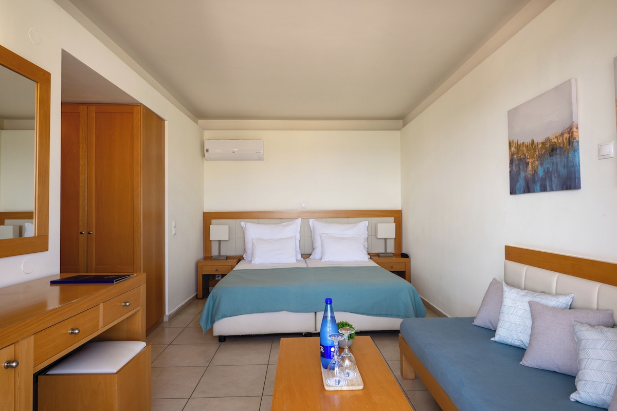 Una habitación de hotel con una cama, un sofá, un escritorio y un espejo.