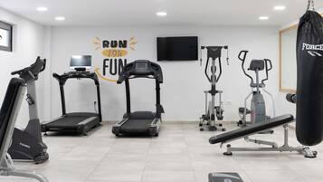 Een fitnessruimte met loopbanden, een hometrainer, een roeimachine en een bokszak.