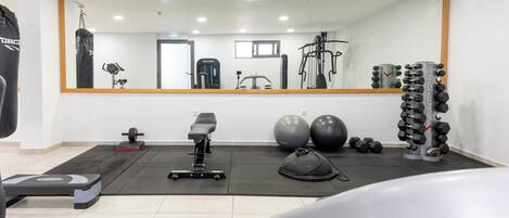 Un gimnasio con equipo de ejercicio, un espejo y un saco de boxeo.