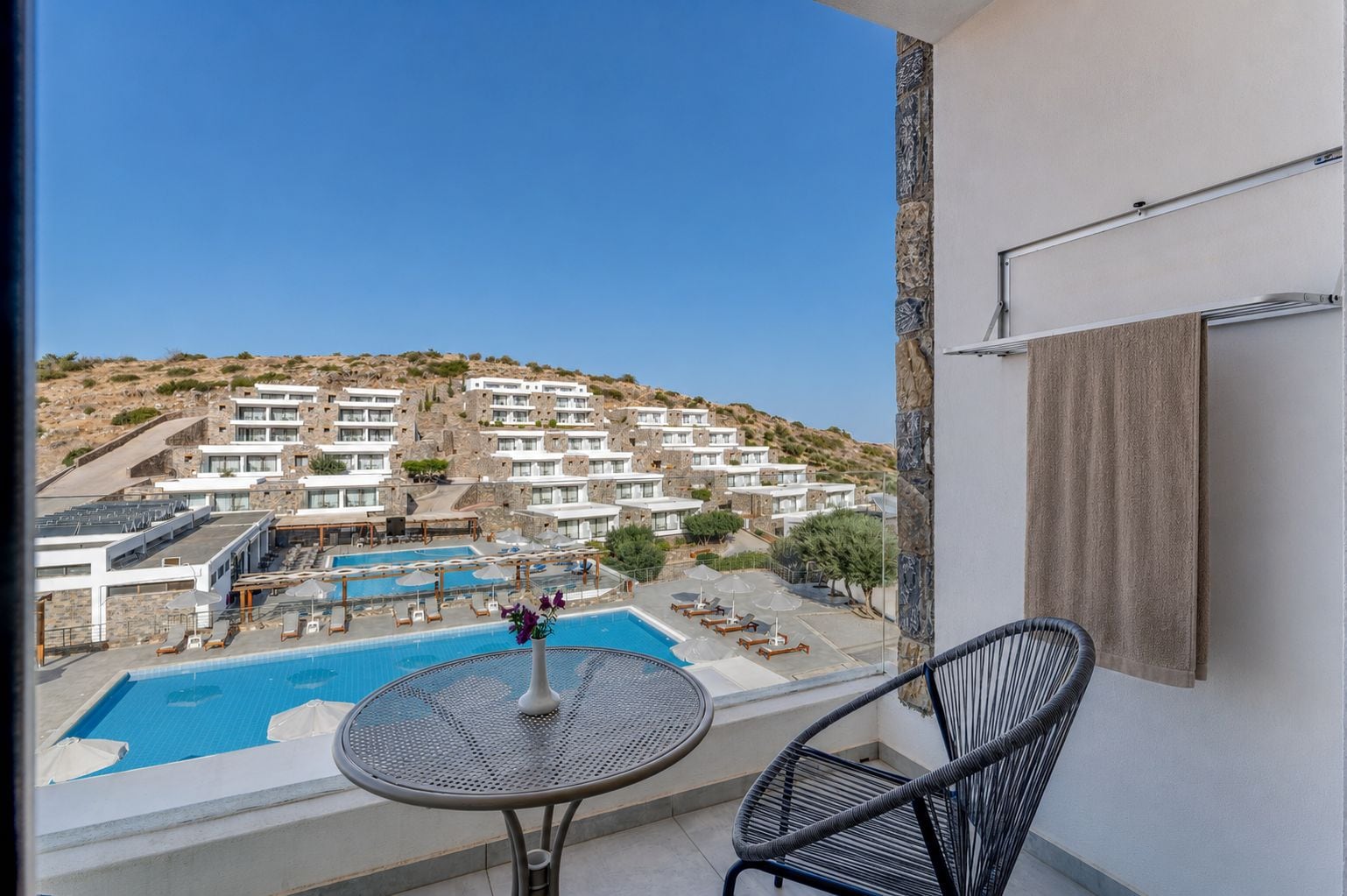 A balcony with a view of a swimming pool and hotel buildings.