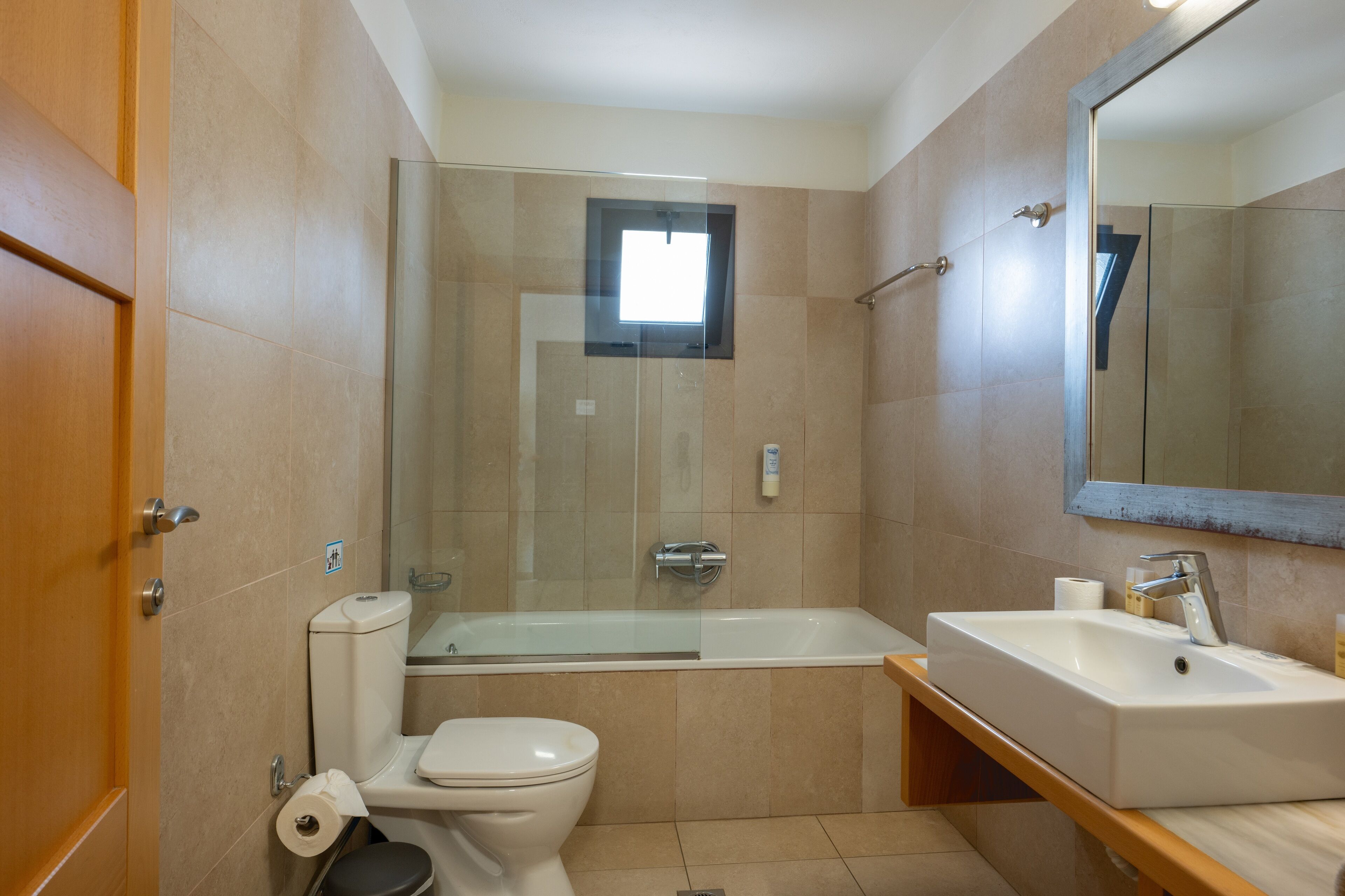 Een moderne badkamer met een douchecabine van glas, een wit toilet en een wastafel met een spiegel erboven.