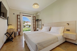 A hotel room with a large bed, a bedside table, a TV mounted on the wall, and a view of the outdoors.