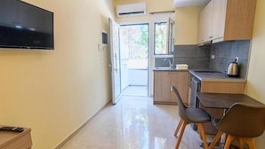 A compact kitchen with a flat-screen TV, a dining area with two chairs, and a kitchenette. - Varvaras Diamond (Rethymno)
