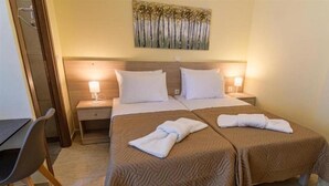 A hotel room with two beds, a desk, and a chair. - Varvaras Diamond (Rethymno)