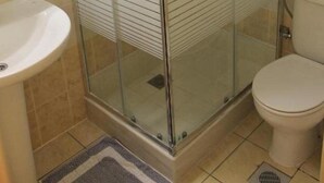 A bathroom with a glass-enclosed shower, a sink, and a toilet. - Varvaras Diamond (Rethymno)