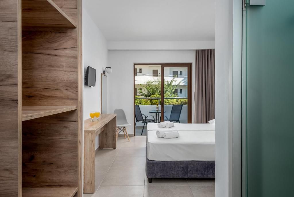 A hotel room with a bed, a desk, a chair, and a view of the outside.