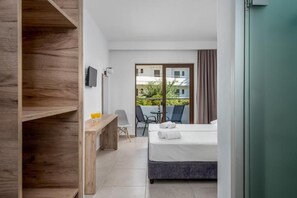 A hotel room with a bed, a desk, a chair, and a view of the outside. - Afandou Blu (Rhodes)