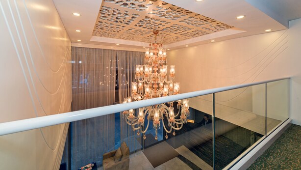 A modern interior with a large chandelier, a glass railing, and a patterned ceiling. - Bisetun Hotel (Istanbul)