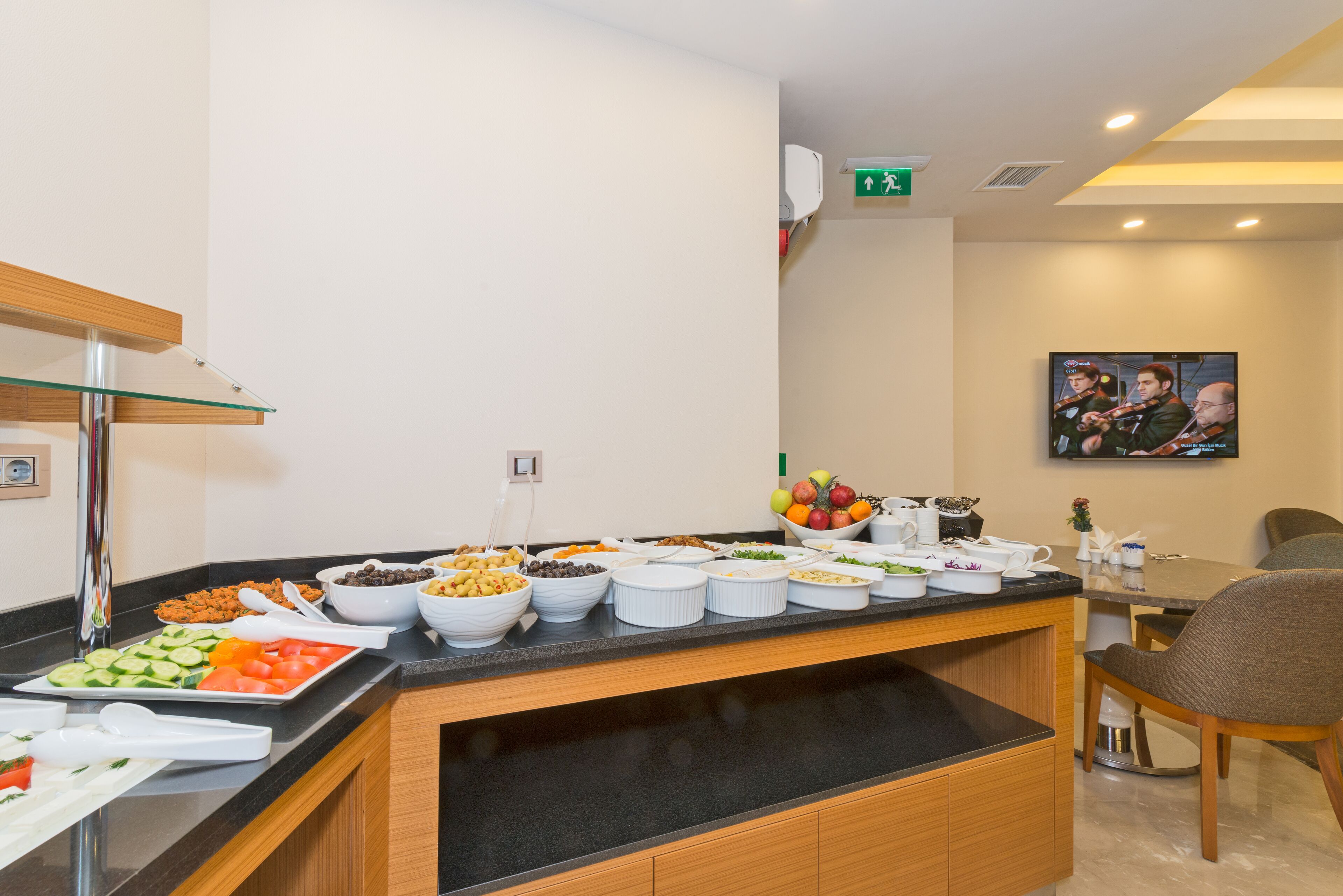 Uma área de buffet com diversos alimentos e uma mesa de jantar com cadeiras.