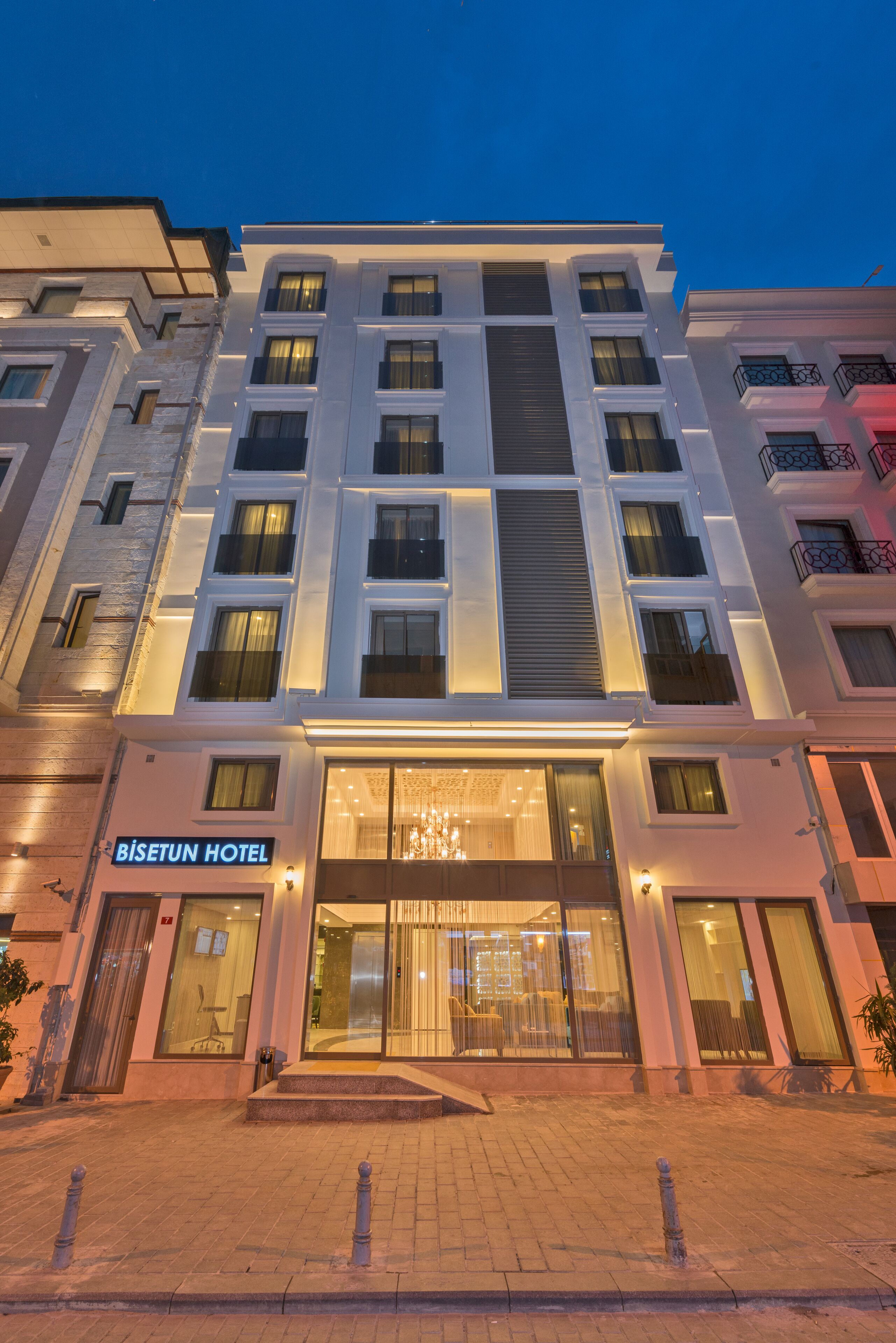 Un hotel moderno con fachada de vidrio, una entrada visible y un letrero que dice "BISETUN HOTEL".