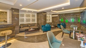 A modern lobby with a curved seating area, a bar with a marble countertop, and a large wall-mounted TV. - Bisetun Hotel (Istanbul)