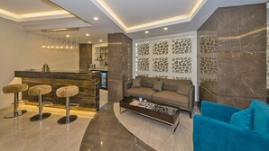 A modern lobby with a reception desk, bar stools, a sofa, and a coffee table. - Bisetun Hotel (Istanbul)