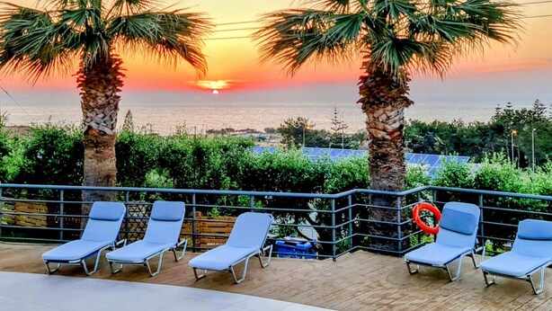 A sunset view with palm trees and lounge chairs on a balcony. - Oasis Scaleta Hotel (Rethymno)