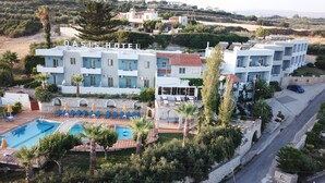 A hotel with a pool, outdoor seating, and a view of the surrounding landscape. - Oasis Scaleta Hotel (Rethymno)