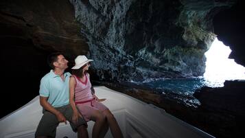 A couple in a boat inside a cave with a view of the ocean.