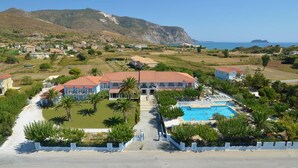 A resort with a swimming pool, palm trees, and a view of the sea. - Hotel Sirocco - Adults Only (Zakynthos)