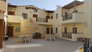 A courtyard with a stone fireplace, outdoor seating, and a pool. - Matheos Apartments (Hersonissos)