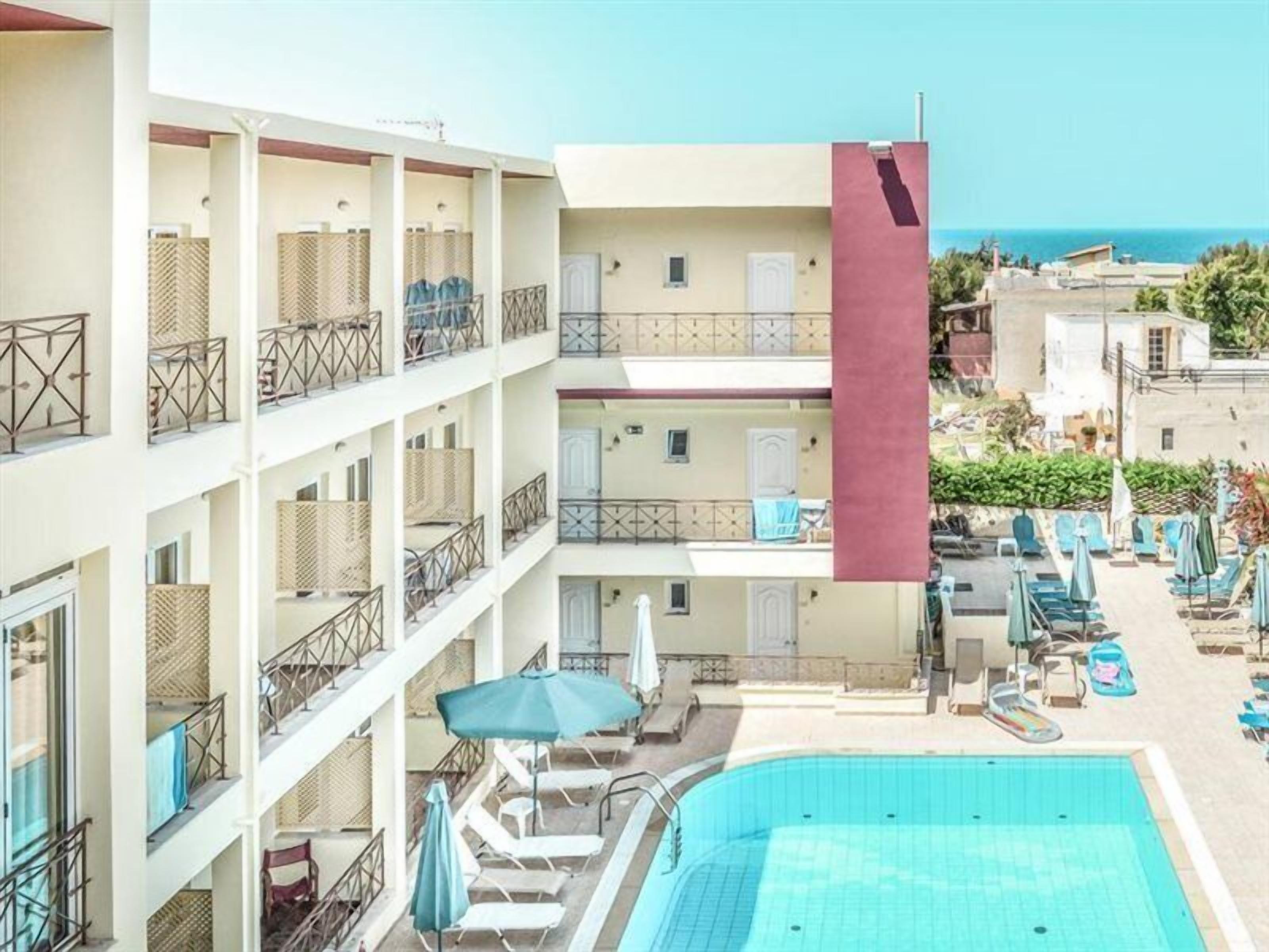 A multi-story hotel with balconies, a swimming pool, and sun loungers.