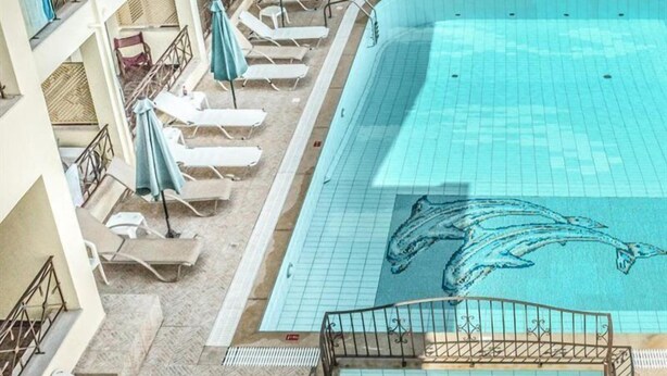 A swimming pool with a dolphin mural, lounge chairs, and a tiled deck. - Alexandros (SISSI)