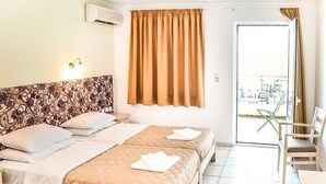 A hotel room with two beds, a patterned headboard, a window with curtains, a balcony with chairs, and an air conditioning unit. - Alexandros (SISSI)