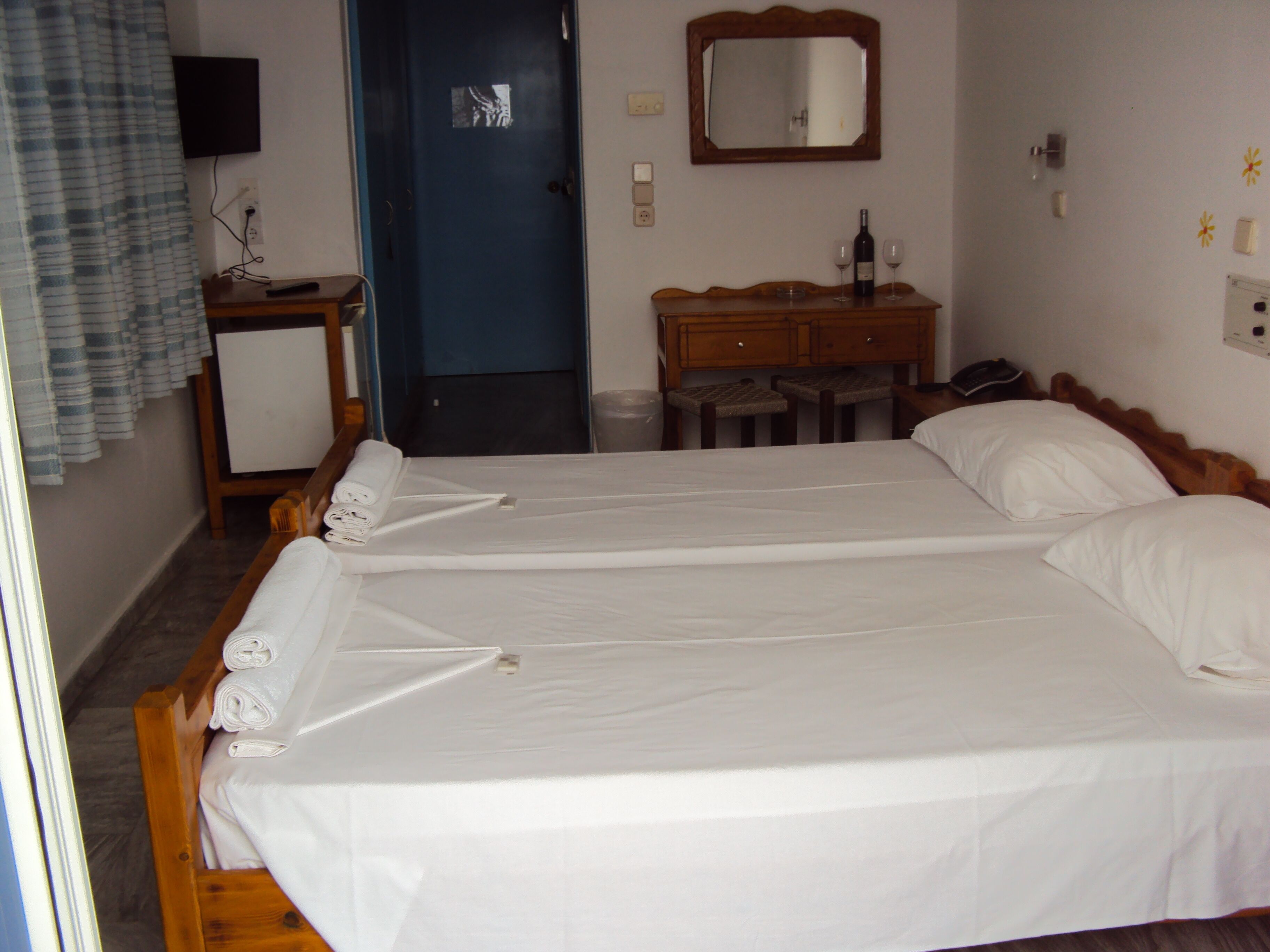 Een hotelkamer met een tweepersoonsbed, een houten dressoir, een spiegel, een bureau en een televisie.