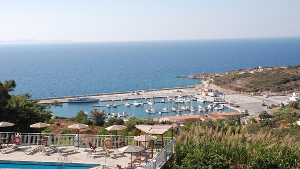 Un puerto deportivo con barcos, piscina y mobiliario exterior con sombrillas.
