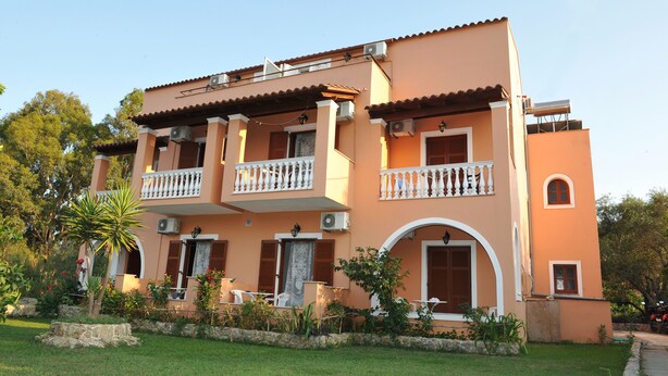 A two-story building with balconies, a stone foundation, and a garden. - Vasso Studios (Corfu)
