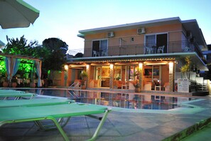 A hotel with a swimming pool, outdoor seating, and a bar/lounge area. - Makis Louvlis Luxury Apartments (Corfu)