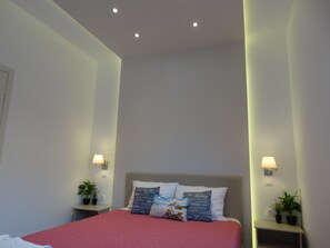 A hotel room with a bed, two bedside tables with lamps, and a ceiling with recessed lighting. - Makis Louvlis Luxury Apartments (Corfu)