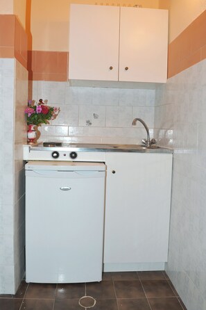 A compact kitchen with a built-in washer and dryer, a sink, and a cabinet above. - Makis Louvlis Luxury Apartments (Corfu)