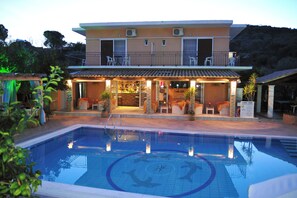 A hotel with a swimming pool, outdoor seating, and a bar area. - Makis Louvlis Luxury Apartments (Corfu)