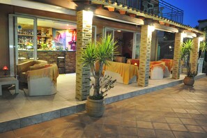 A restaurant with outdoor seating, a bar, and potted plants. - Makis Louvlis Luxury Apartments (Corfu)