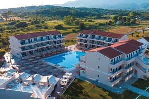 A hotel with multiple balconies, a swimming pool, and outdoor seating areas. - Angela Beach Hotel (Corfu)