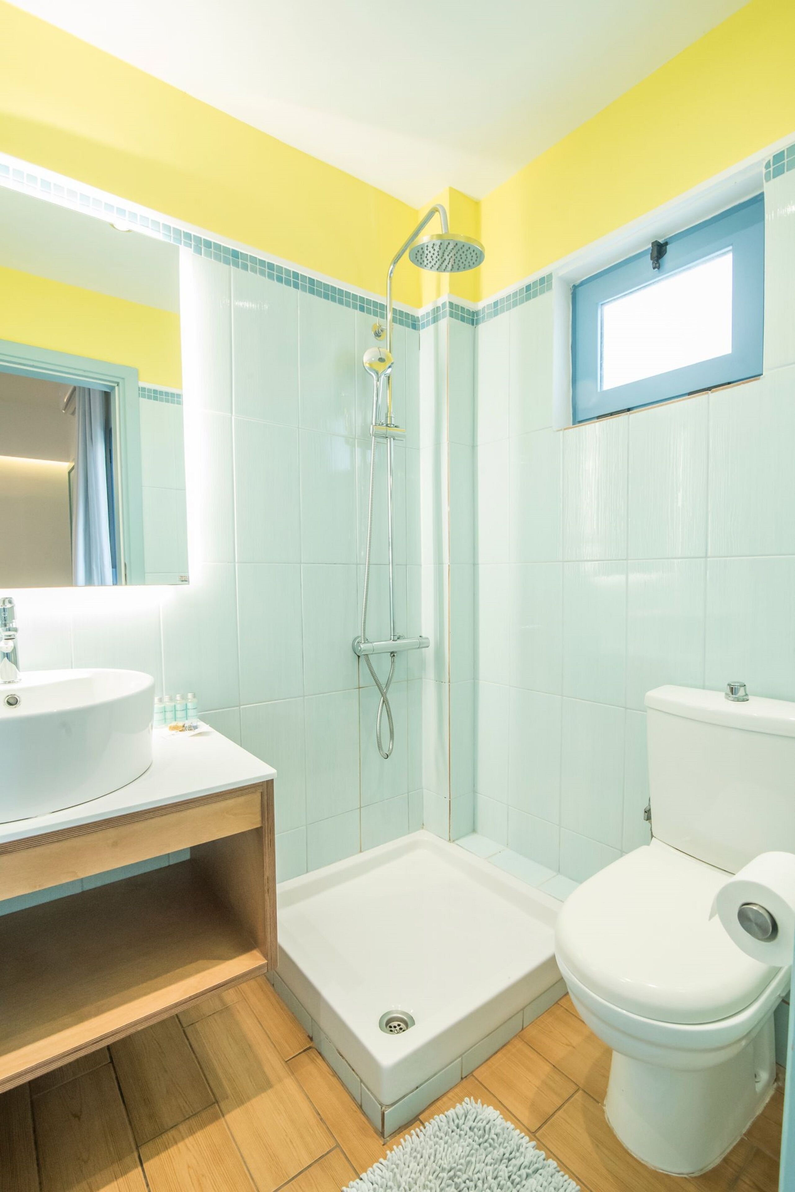 A bathroom with a shower, toilet, sink, and mirror.