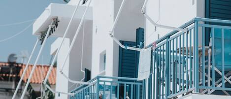 A row of white buildings with blue railings and shutters, likely part of a hotel or resort.