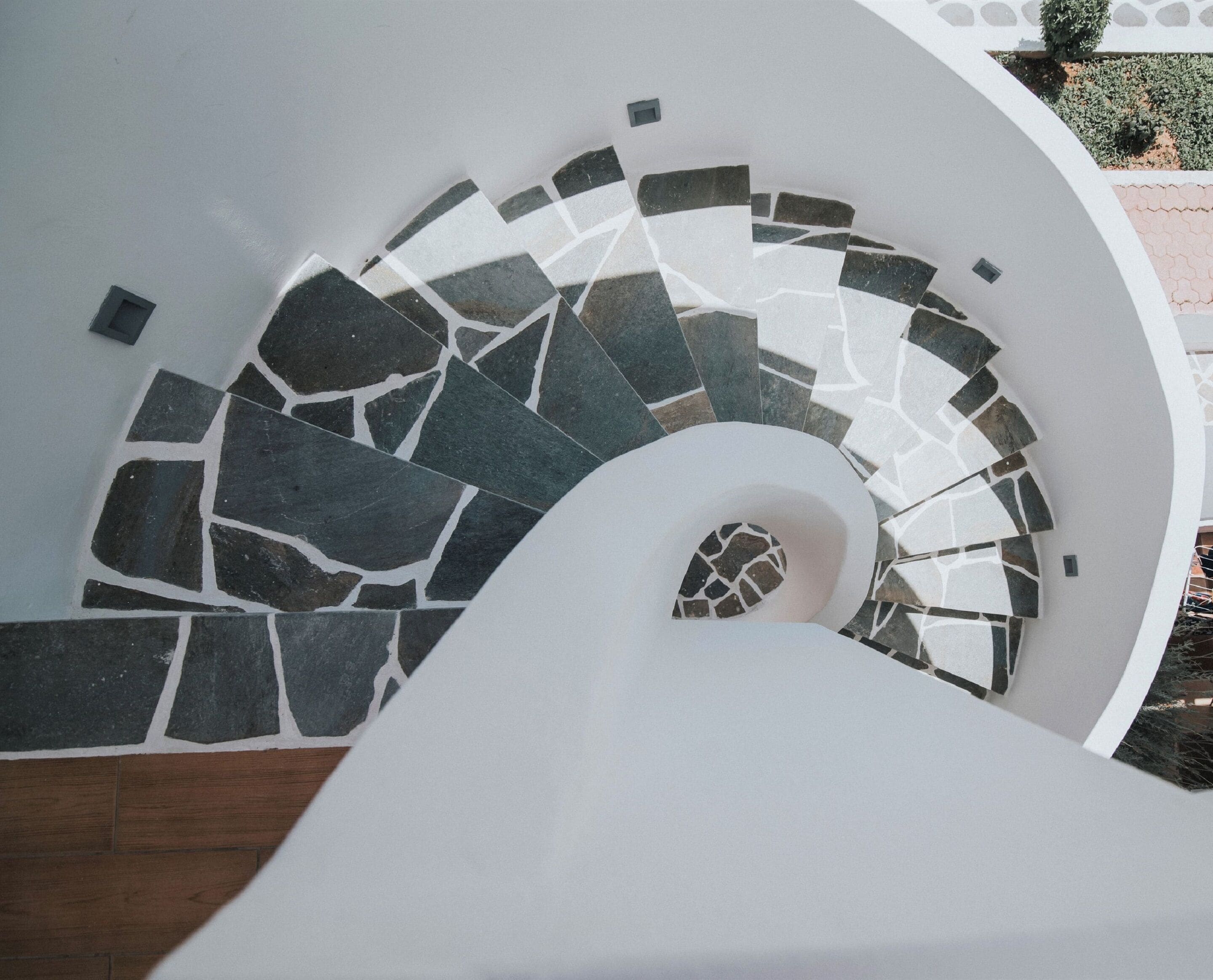 Una escalera de caracol con interior blanco y un diseño de mosaico en el suelo.