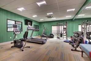 A gym with treadmills, elliptical machines, weight benches, and free weights.