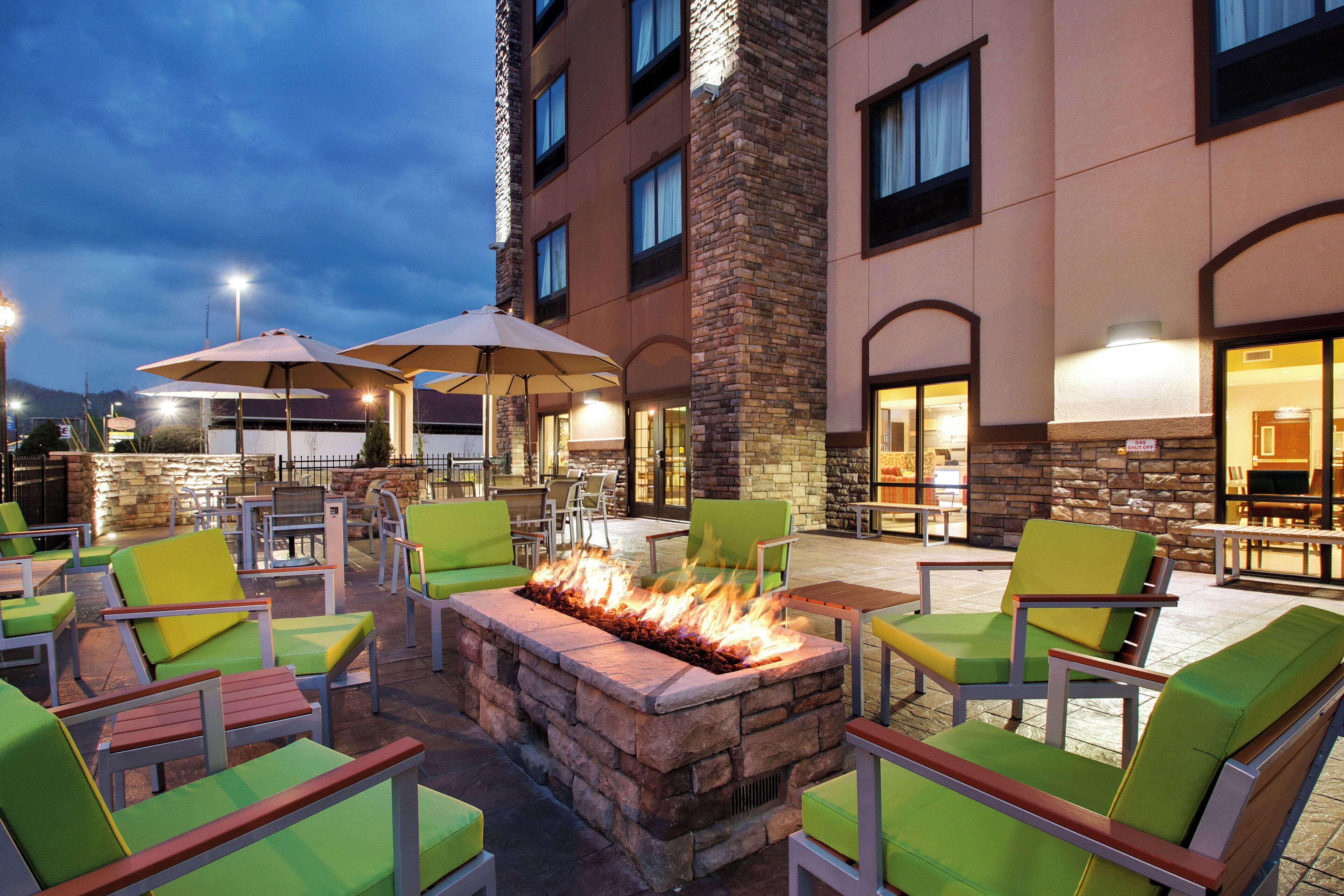 An outdoor seating area with fire pit, chairs, and umbrellas.