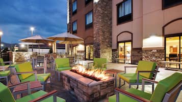 An outdoor seating area with fire pit, chairs, and umbrellas.