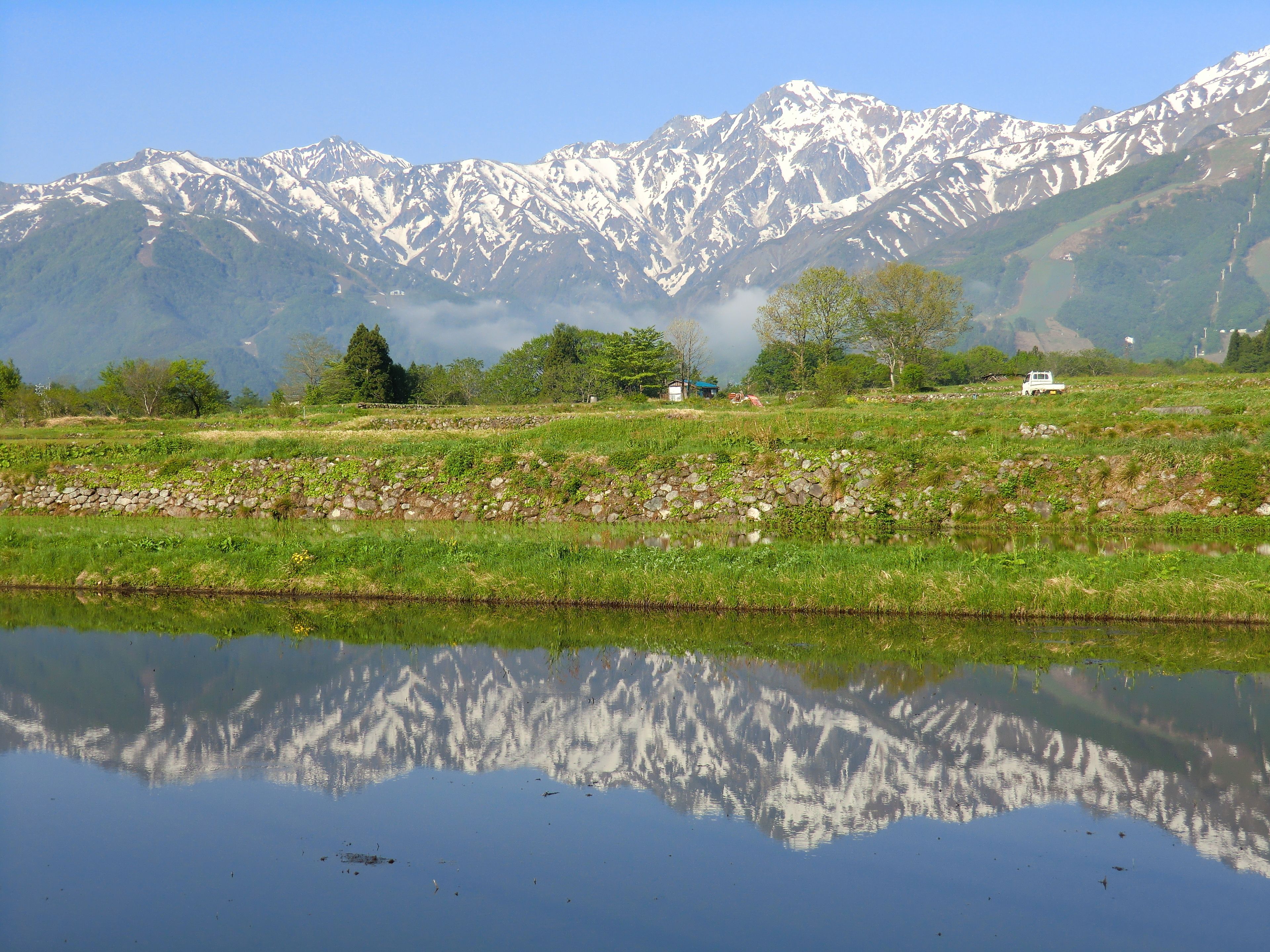 A serene landscape with a clear lake reflecting trees and mountains.