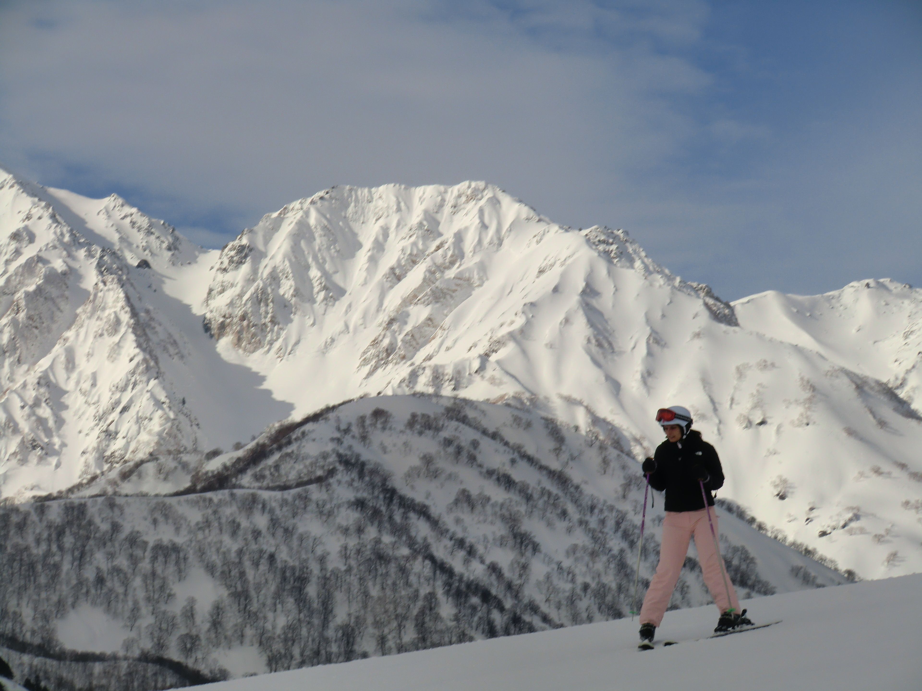 A person skiing on a snowy mountain with a clear sky.