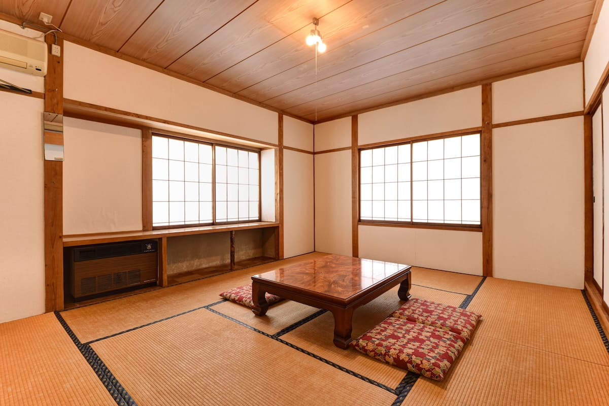 Una habitación japonesa tradicional con suelo de tatami, una mesa de madera baja y puertas correderas shoji.