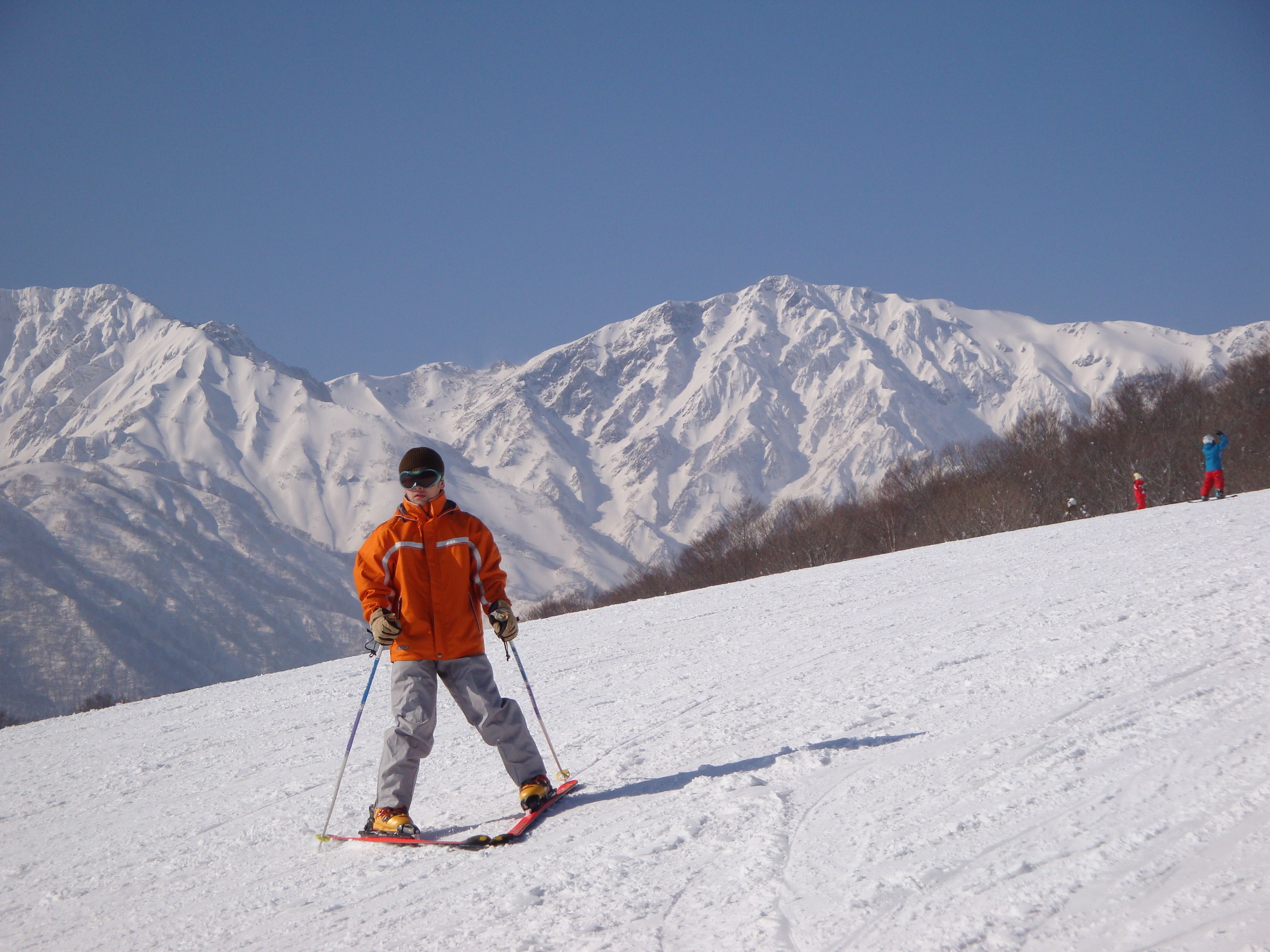 A person skiing on a snowy slope with a mountain range in the background.