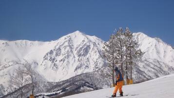 Un snowboarder en una ladera nevada, con una montaña al fondo.