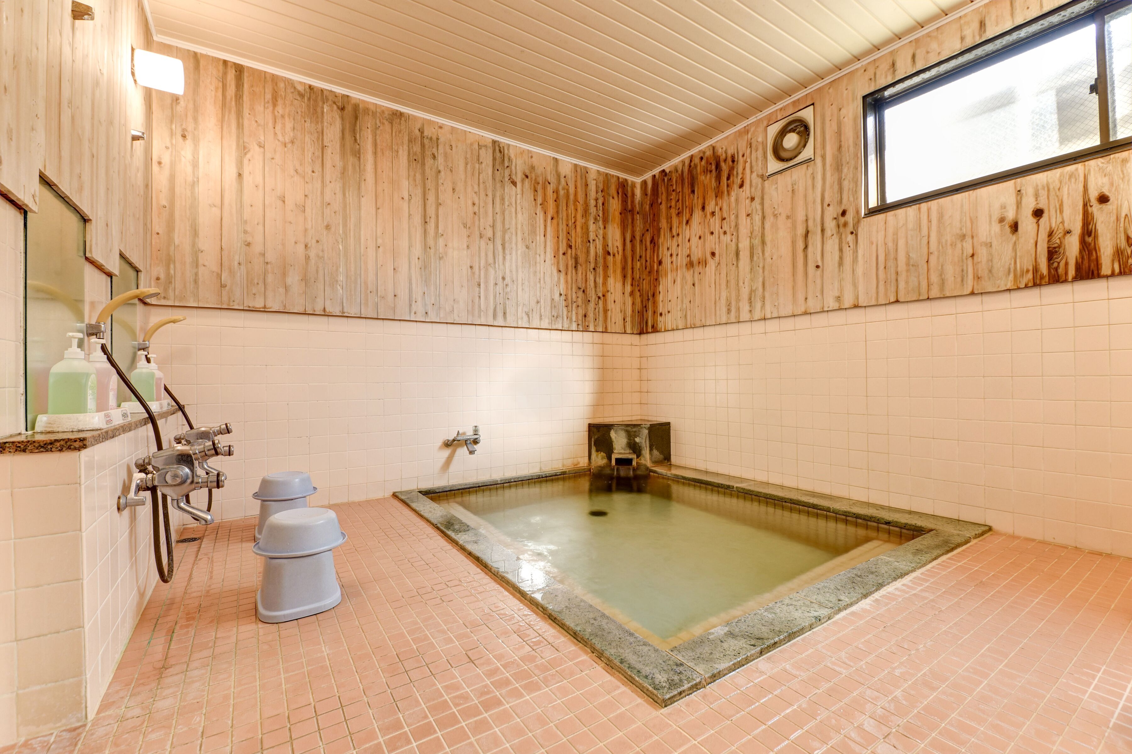 Un baño con paneles de madera, una bañera grande, un inodoro y una zona de ducha.