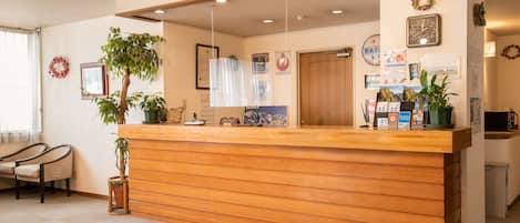 Una reception con un piano di lavoro in legno, una pianta in vaso e un quadro appeso al muro.