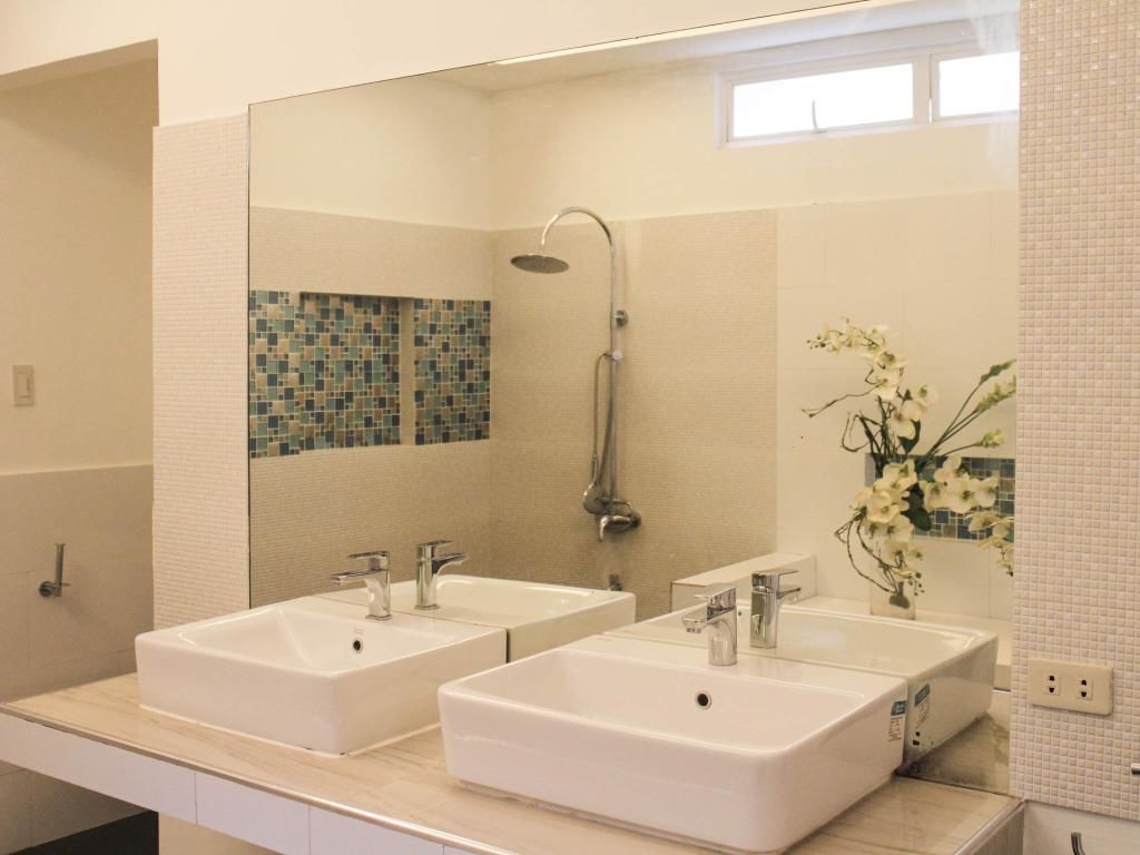 Un baño con dos lavamanos, una ducha y un espejo.