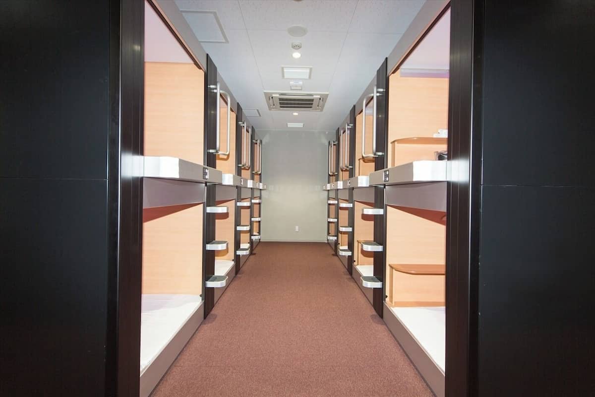 A corridor with bunk beds, a carpeted floor, and ceiling lights.