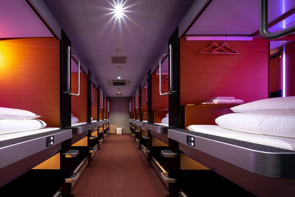 Un wagon-lit doté de plusieurs couchettes, chacune équipée d’un panneau de commande, d’une barre de maintien et d’une tête de lit.